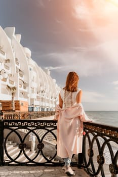 Woman travel sea. Young Happy woman in a long red dress posing on a beach near the sea on background of volcanic rocks, like in Iceland, sharing travel adventure journey