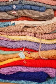 stack of knitted warm sweaters with different knitting patterns..