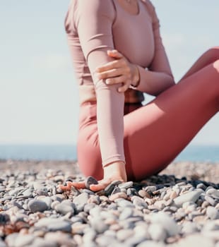 Young woman with long hair in white swimsuit and boho style braclets practicing outdoors on yoga mat by the sea on a sunset. Women's yoga fitness routine. Healthy lifestyle, harmony and meditation