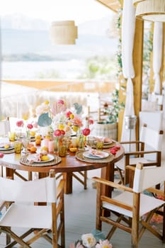 Round festive table with chairs stands on the hotel terrace by the sea. High quality photo