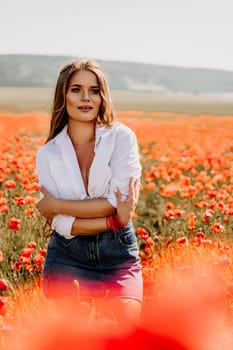 Happy woman in a poppy field in a white shirt and denim skirt with a wreath of poppies on her head posing and enjoying the poppy field