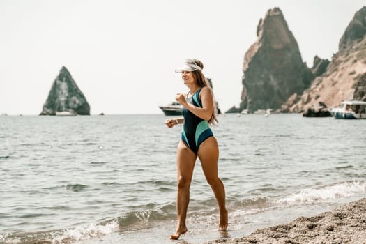 Woman beach vacation photo. A happy tourist in a blue bikini enjoying the scenic view of the sea and volcanic mountains while taking pictures to capture the memories of her travel adventure