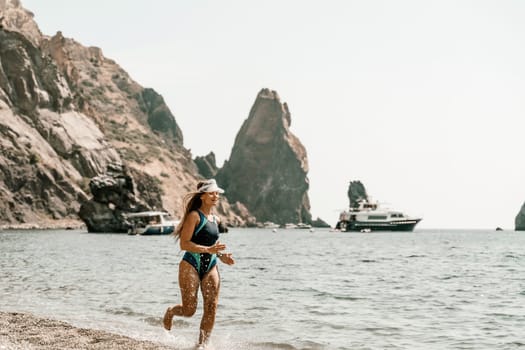 Woman beach vacation photo. A happy tourist in a blue bikini enjoying the scenic view of the sea and volcanic mountains while taking pictures to capture the memories of her travel adventure