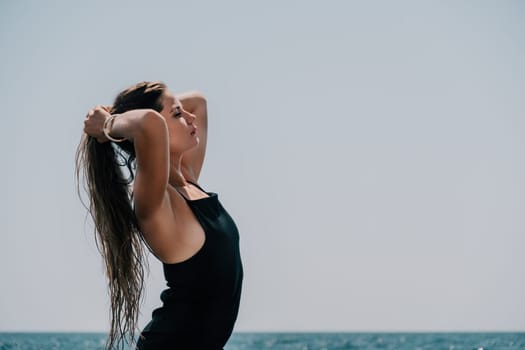 Woman travel sea. Young Happy woman in a long red dress posing on a beach near the sea on background of volcanic rocks, like in Iceland, sharing travel adventure journey