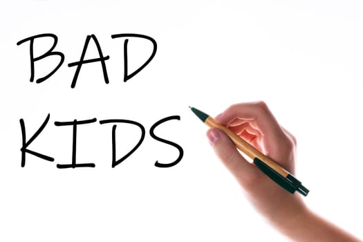 Children hand with pen write on a blue white background. Writing hand. Word Bad kids
