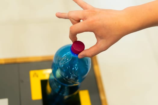 Close up hand throwing an empty plastic water bottle into recycling bin, recycle rubbish