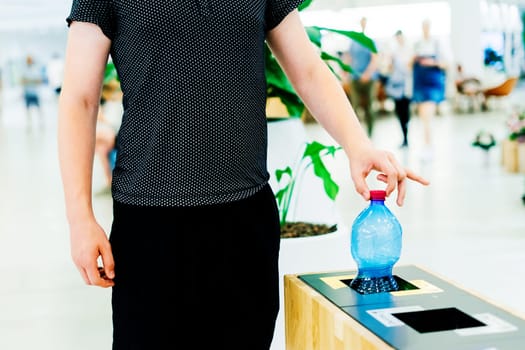 Close up hand throwing an empty plastic water bottle into recycling bin, recycle rubbish