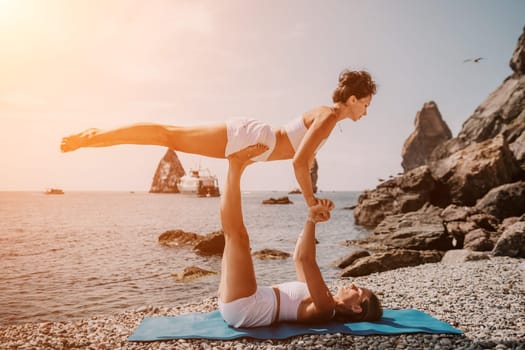 Woman sea yoga. Back view of free calm happy satisfied woman with long hair standing on top rock with yoga position against of sky by the sea. Healthy lifestyle outdoors in nature, fitness concept.