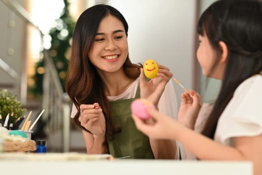 Beautiful mother and little daughter decorating easter eggs at home. Happy Easter concept