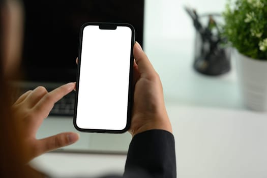 Female worker using mobile phone at her office desk. Closeup, blank screen for your advertising text