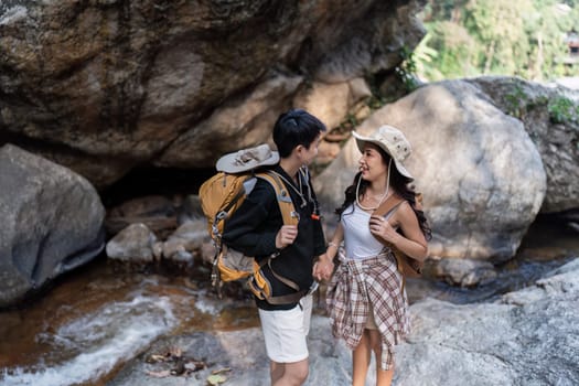 Happy LGBT Lesbian couple Travelers Hiking with Backpacks in waterfall Trail. LGBT Lesbian Couple Hikers with backpacks walks in mountains in vacation.