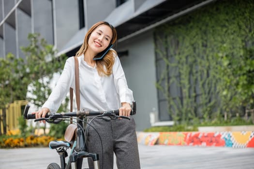 Amidst urban scenery a cheerful woman enjoys a bike ride while staying connected through her smartphone. The seamless blending of work joy and technology is evident in her expression.