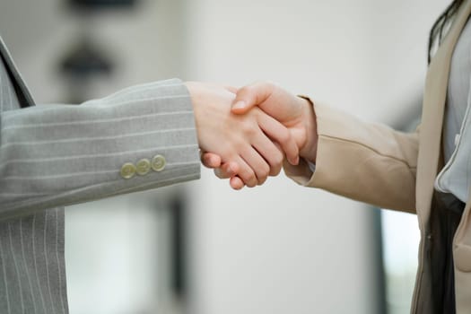 Close-up view of a firm handshake between two businesswomen, representing a professional agreement or partnership.