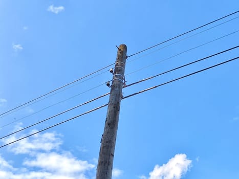 Old power line pole against blue sky in a nice sunny day