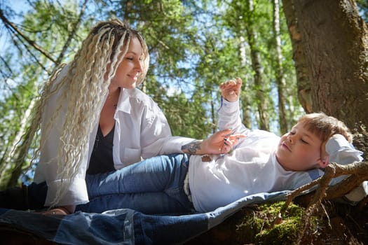 Kirov, Russia - June 12, 2023: Funny mother with dreadlocks and fat boy happy walking in the forest on sunny summer day