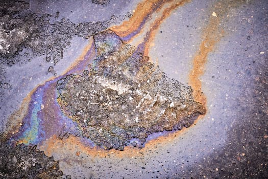 Background of a puddle of gasoline spilled on the road. Gasoline leak. A colorful stain of engine oil on the road