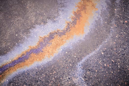 Textured stain of fuel or oil on wet asphalt on a rainy day. The concept of environmental pollution.