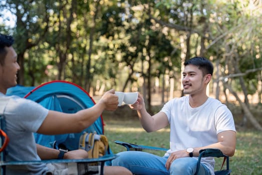 Male gay couple asian traveling with tent camping outdoor and various adventure lifestyle hiking active summer vacation. drinking coffee and talking together.