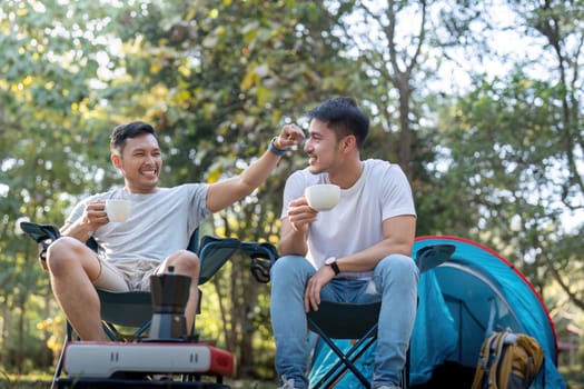 Male gay couple asian traveling with tent camping outdoor and various adventure lifestyle hiking active summer vacation. drinking coffee and talking together.