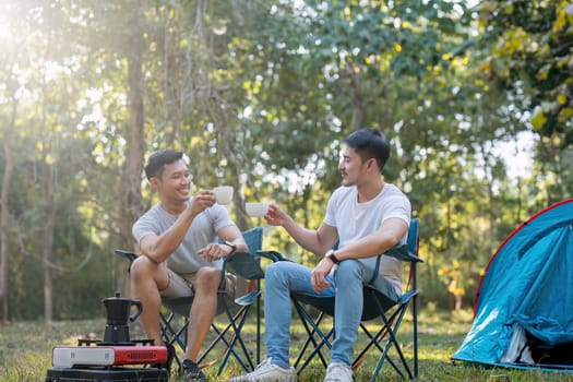 Male gay couple asian traveling with tent camping outdoor and various adventure lifestyle hiking active summer vacation. drinking coffee and talking together.