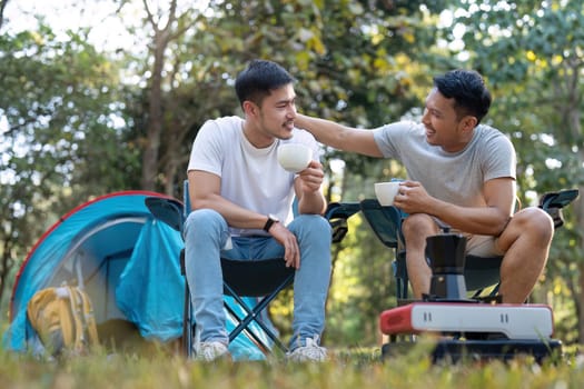 Male gay couple asian traveling with tent camping outdoor and various adventure lifestyle hiking active summer vacation. drinking coffee and talking together.