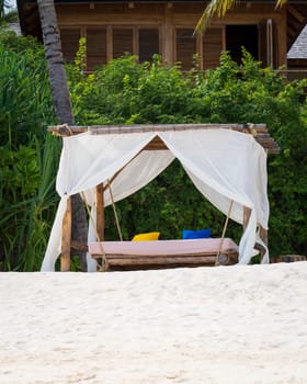 White beach canopy at sunset. Luxury beach tents at luxurious beach resort. Summer beach concept, carefree, rest seaside, Nobody on the beach.Garden on the back.