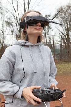 LVIV, UKRAINE - Feb. 11, 2024: A young woman is seen wearing virtual reality goggles and a remote control while learning to fly an FPV drone