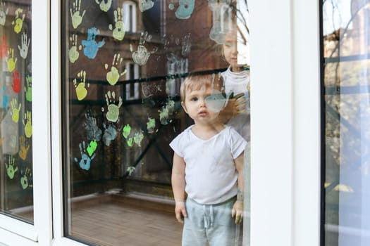 A boy paints with palms on the window. Quarantine Stay at home