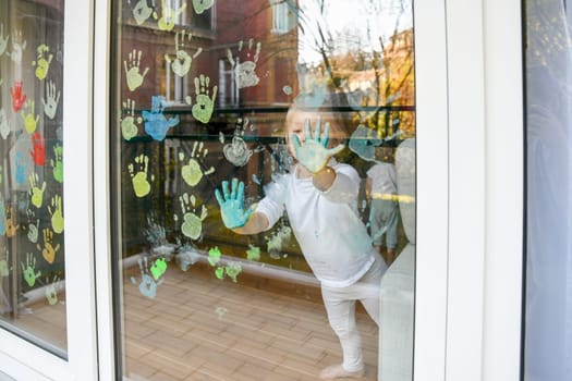 Girl paints with palms on the window. Quarantine Stay at home