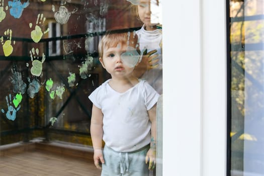 A boy paints with palms on the window. Quarantine Stay at home