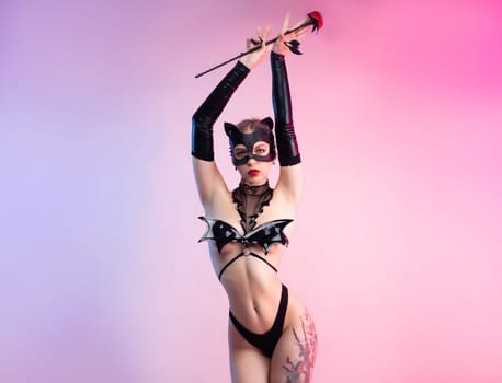 Sexy girl in lingerie, leather cat mask for BDSM costume for sex games on a pink bright background copy paste