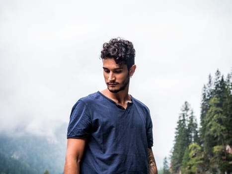 A man with curly hair wearing a black shirt. Photo of a stylish man with curly hair wearing a black jacket against the stunning backdrop of the Dolomites in Italy