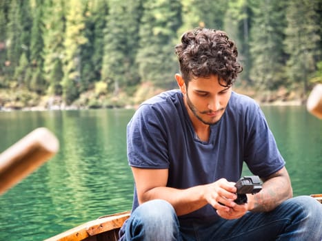A man standing on a boat holding a camera. Photo of a man capturing the breathtaking beauty of the Dolomites from a boat in Italy