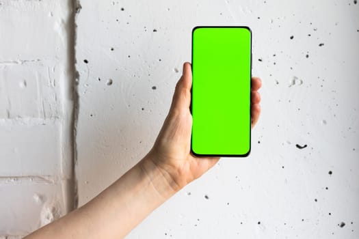 Mockup image of a person holding smart mobile phone with blank green screen