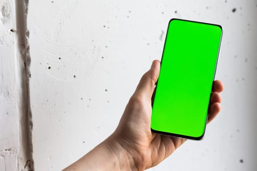 Mockup image of a person holding smart mobile phone with blank green screen