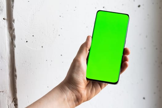 Mockup image of a person holding smart mobile phone with blank green screen