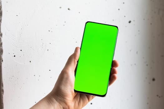 Mockup image of a person holding smart mobile phone with blank green screen