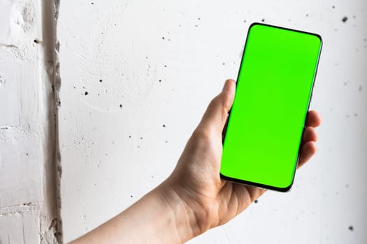 Mockup image of a person holding smart mobile phone with blank green screen