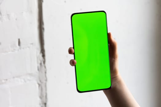 Mockup image of a person holding smart mobile phone with blank green screen