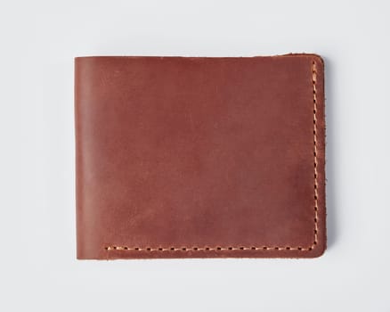 Closeup of stylish slim mens custom billfold wallet made of genuine copper colored leather with decorative stitching and William name embossed on light background