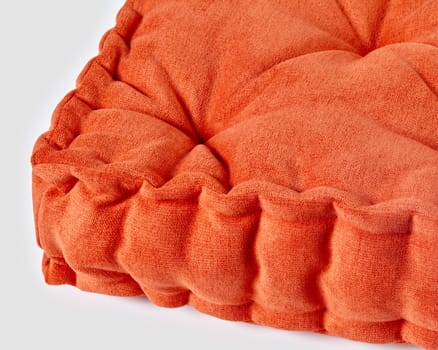 Close-up view of vibrant orange linen cushion with soft texture, ideal for adding pop of color to home interiors. Handcrafted accessory for comfortable seating area