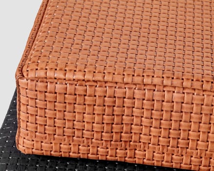 Close-up image of woven texture of handmade artisanal tan leather cushion, highlighting quality and luxurious feel. Modern accessories for interior design