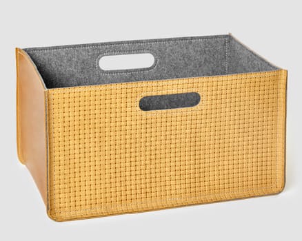 Functional comfortable storage bin with tan braided suede exterior and soft grey felt lining on white background. Stylish interior accessory for organizing space