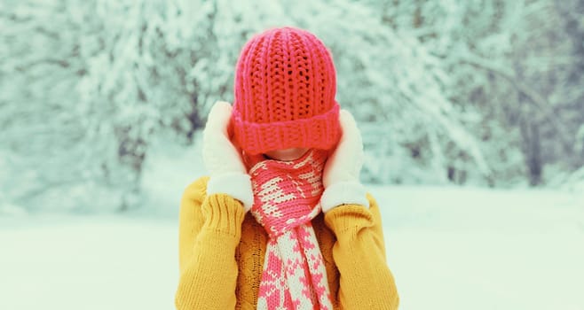 Winter portrait of happy cheerful smiling young woman having fun in colorful knitted hat, scarf enjoys weather in snowy park
