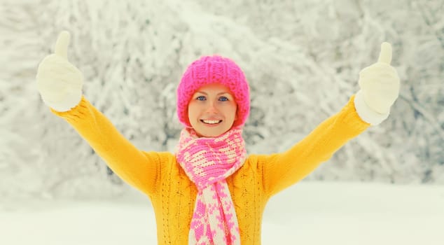 Winter portrait of happy cheerful smiling young woman having fun in colorful knitted hat, scarf enjoys weather in snowy park