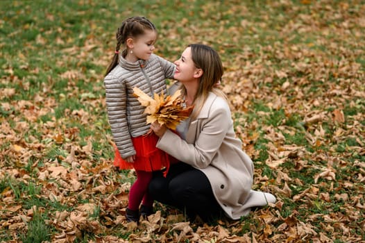 Autumn portrait of mother and daughter in the park, happy mother and daughter.