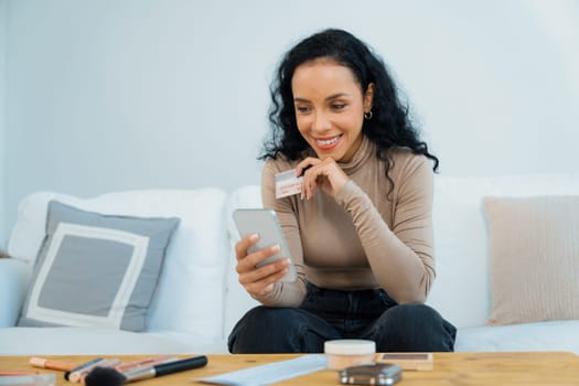 Young happy woman buy product by online shopping at home while ordering items from the internet with credit card online payment system protected by crucial cyber security from online store platform