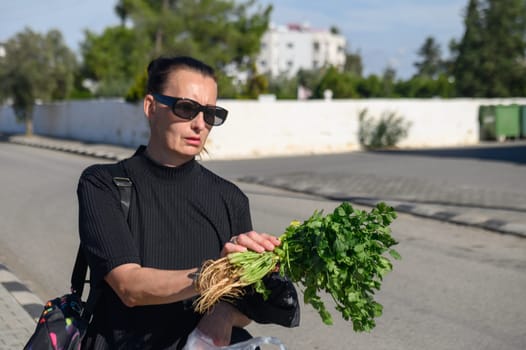 a woman in a black jacket and glasses walks through a village in Cyprus in winter 1