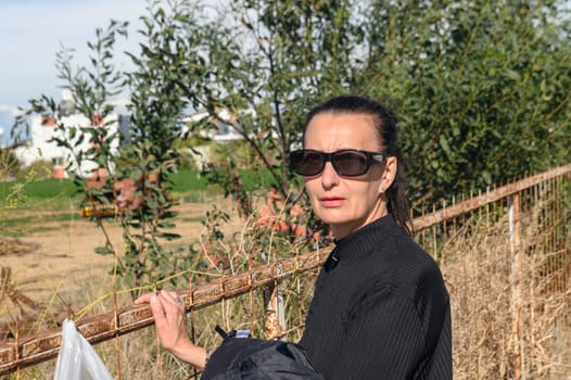 a woman in a black jacket and glasses walks through a village in Cyprus in winter