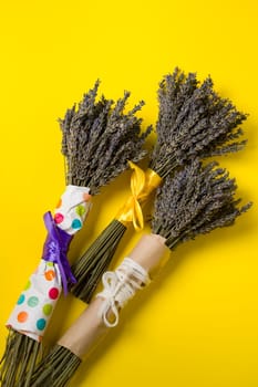 Three bouquets of dried lavender on a yellow background, lavender is a cosmetic plant.